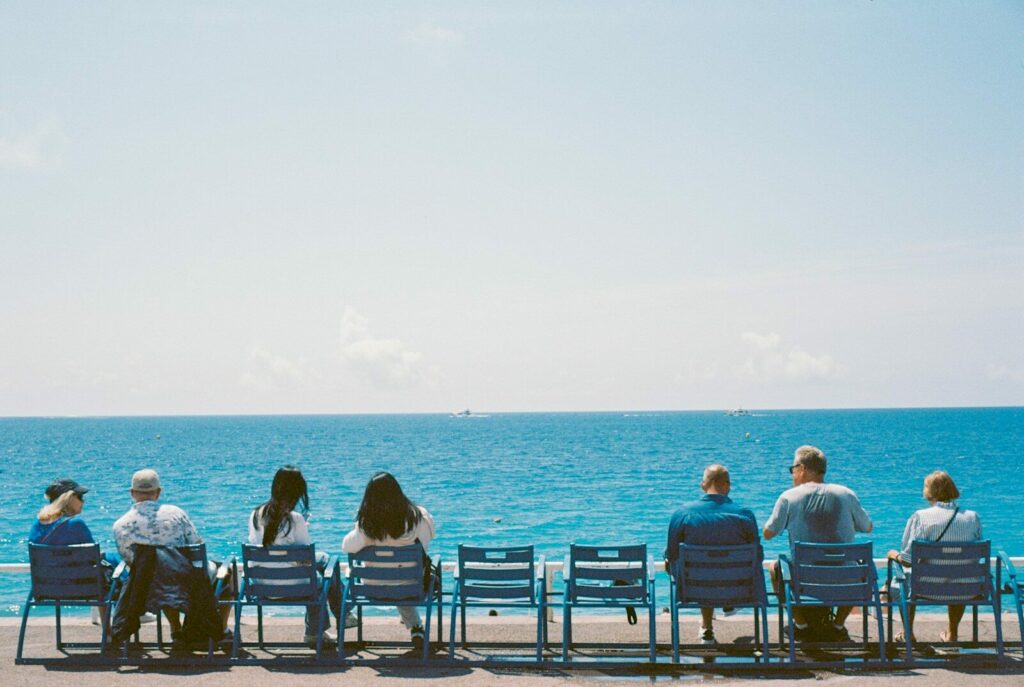 a group of people sitting on top of a bench next to the ocean